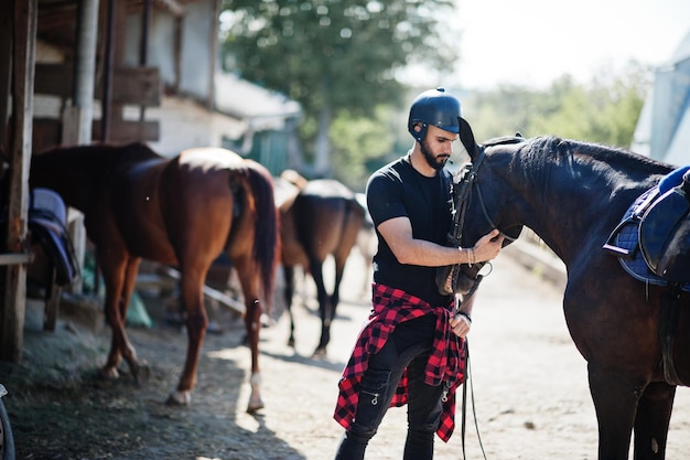 Foto grátis homem de barba alta árabe usa capacete preto com cavalo árabe