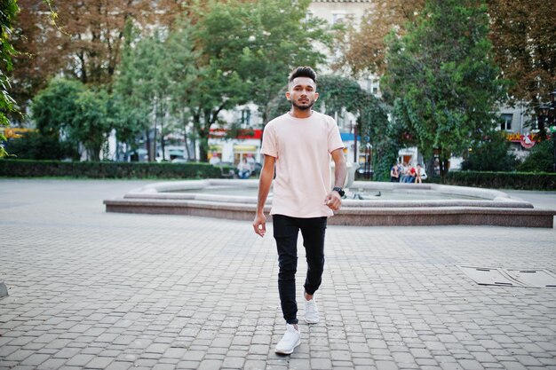 Homem de barba indiana elegante em camiseta rosa modelo Índia posou ao ar livre nas ruas da cidade