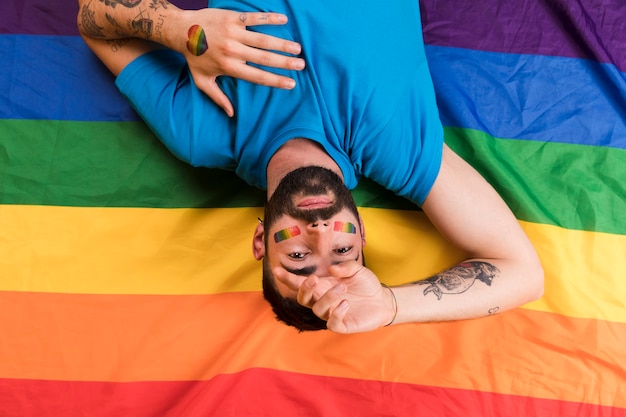 Foto grátis homem de cabeça para baixo com símbolo colorido de lgbt e tatuagem