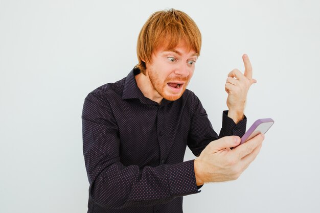 Homem de cabelo vermelho indignado com smartphone