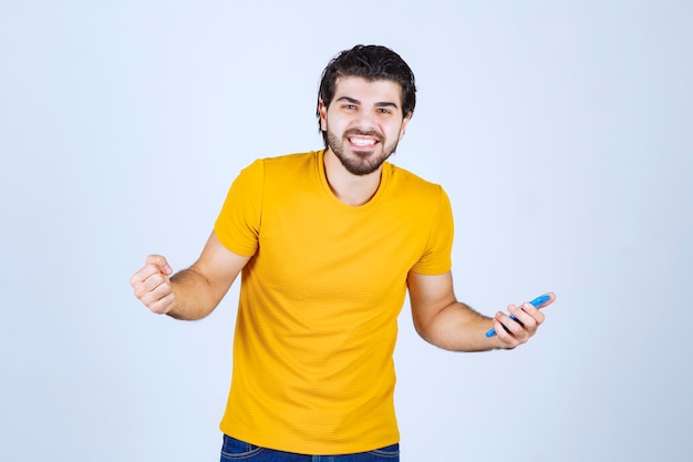 Homem de camisa amarela apontando seu smartphone e gostando.