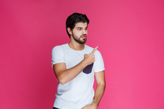 Homem de camisa branca, apontando e apresentando algo no lado direito.