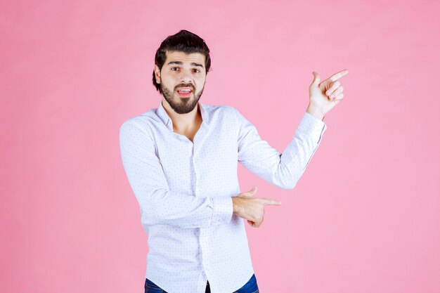 Homem de camisa branca, apontando para o lado direito.