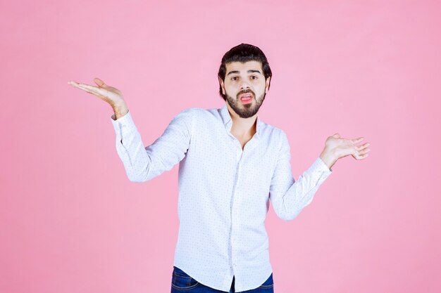 Homem de camisa branca, apontando para os dois lados.