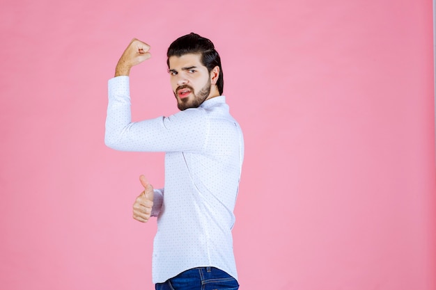 Homem de camisa branca, demonstrando os músculos do braço.