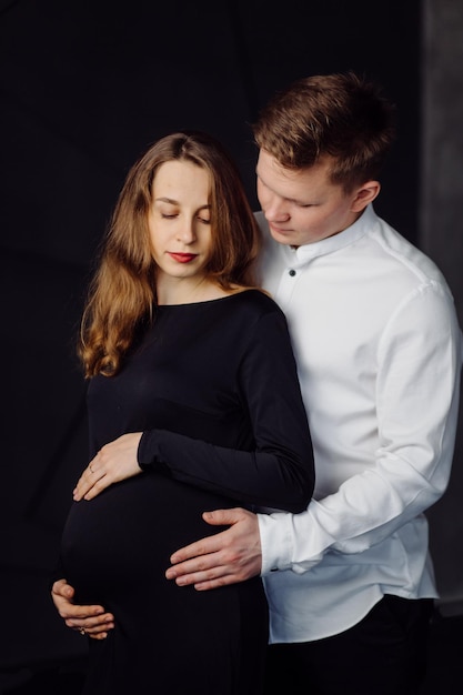 Homem de camisa branca e mulher de vestido preto Foto de gravidez
