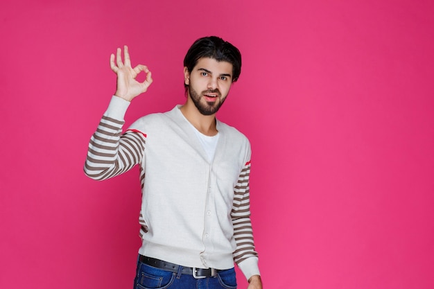 Homem de camisa branca, fazendo sinal de satisfação total ou meditação com a mão.