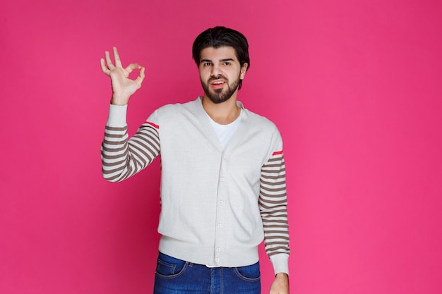 Homem de camisa branca, fazendo sinal de satisfação total ou meditação com a mão.