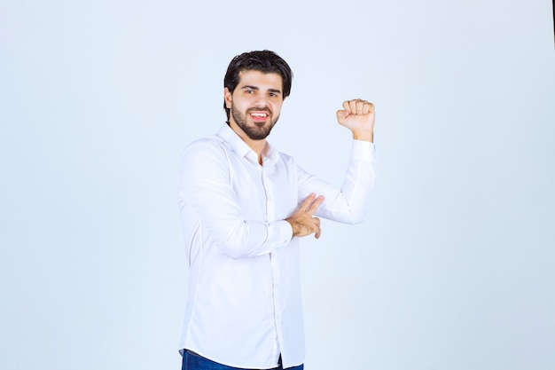 Homem de camisa branca, mostrando os músculos do braço e o punho.