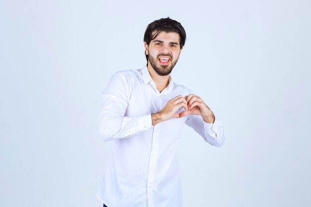 Homem de camisa branca mostrando seu coração e enviando amor