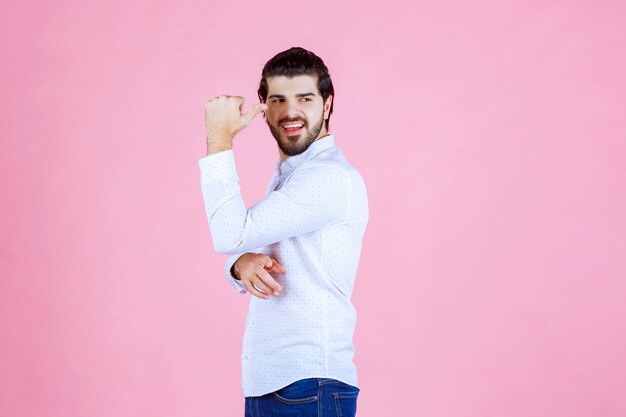 Homem de camisa branca, mostrando seus músculos e força.