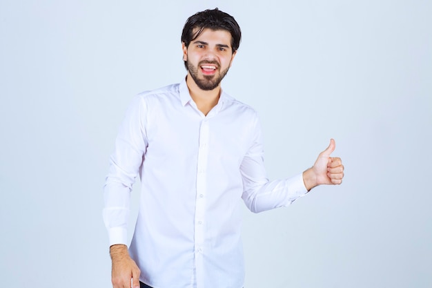Foto grátis homem de camisa branca mostrando sinal de prazer
