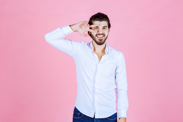 Homem de camisa branca, olhando por entre os dedos.