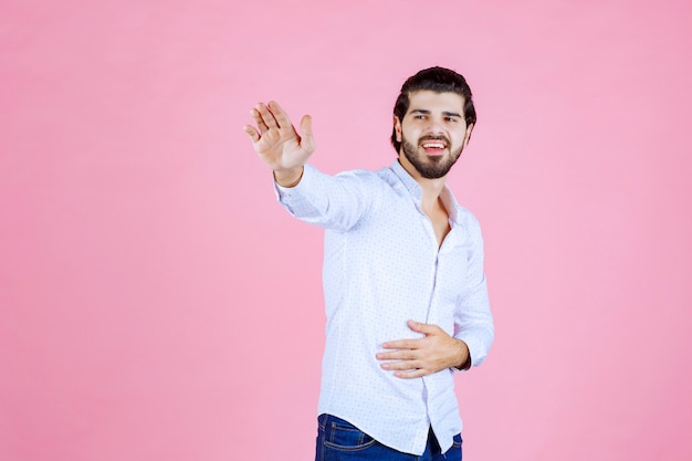 Homem de camisa branca, parando alguma coisa.