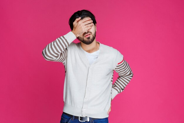 Homem de camisa branca parece exausto e com sono.