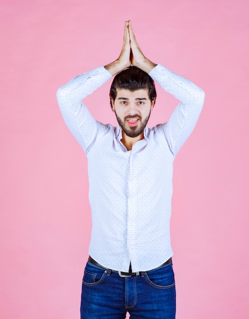 Foto grátis homem de camisa branca, unindo as mãos e orando ou pedindo algo.