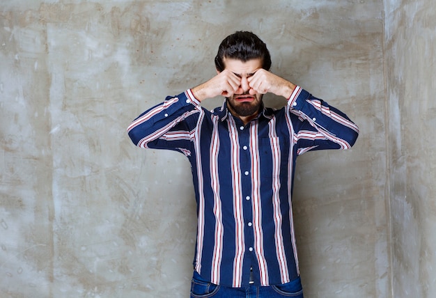 Homem de camisa listrada chorando e se sentindo triste.