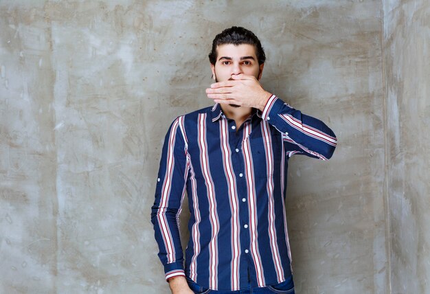 Homem de camisa listrada parece assustado e emocionado.