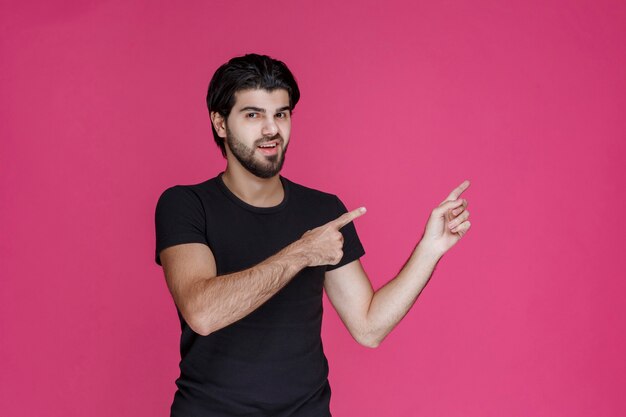 Homem de camisa preta apontando para algo ou apresentando alguém