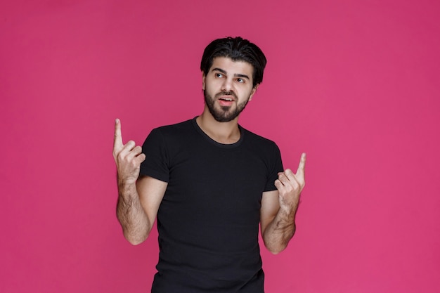 Foto grátis homem de camisa preta demonstrando ou apontando algo