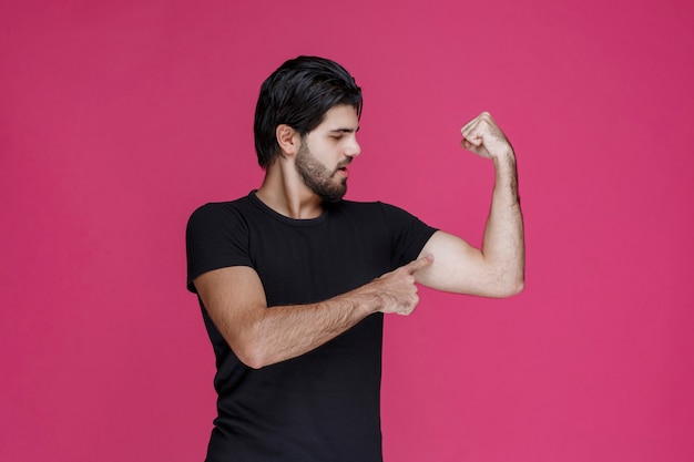 Homem de camisa preta mostrando os músculos do braço