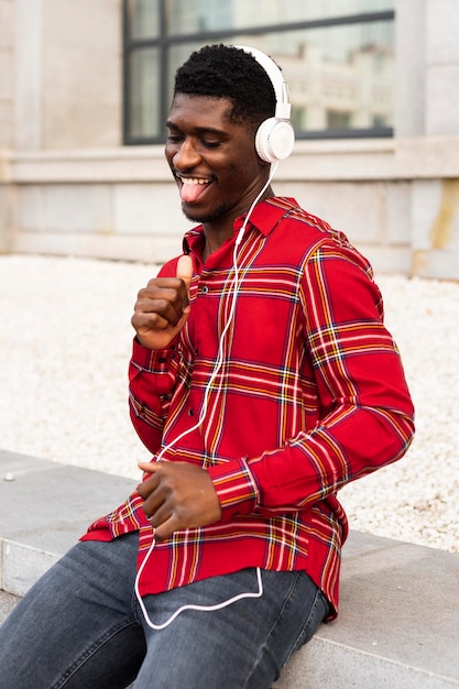 Foto grátis homem de camisa vermelha dançando com seus fones de ouvido