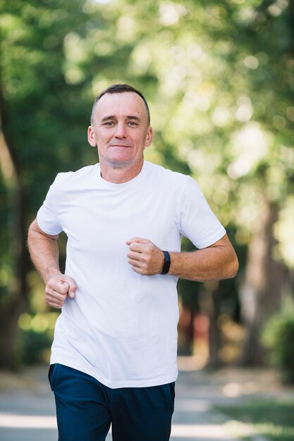 Homem de camiseta branca correndo em um parque