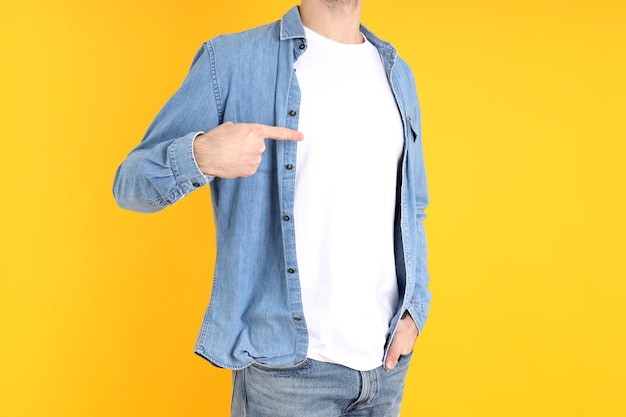 Homem de camiseta em branco e de camisa em fundo amarelo