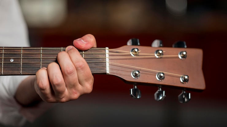 Foto grátis homem de close-up segurando um acorde na guitarra
