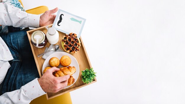 Homem de colheita com bandeja tomando café da manhã