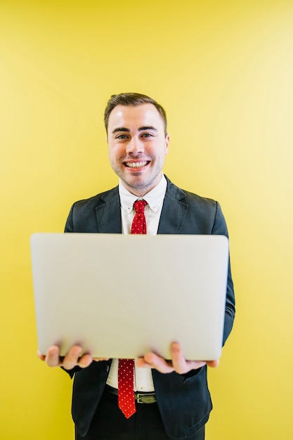 Foto grátis homem de conteúdo com laptop em amarelo