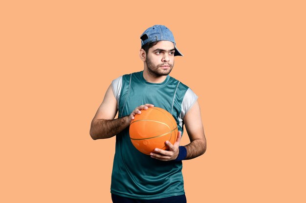 Homem de esportes segurando basquete e desviar o olhar modelo paquistanês indiano