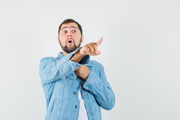 Foto grátis homem de estilo retro com jaqueta, camiseta apontando para longe e parecendo assustado, vista frontal.