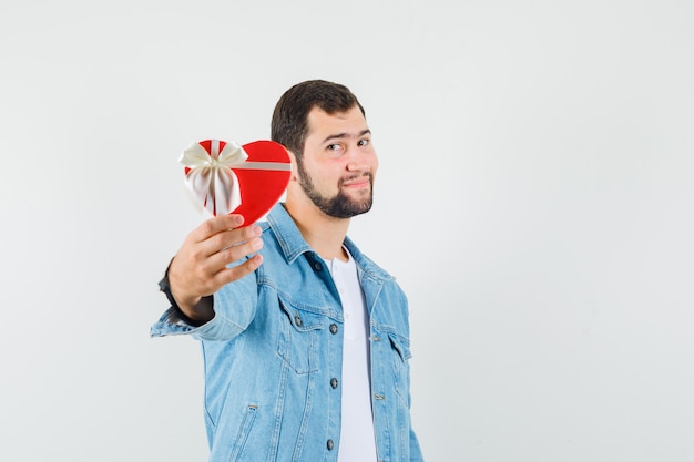 Homem de estilo retro mostrando a caixa de presente na jaqueta, camiseta, vista frontal.