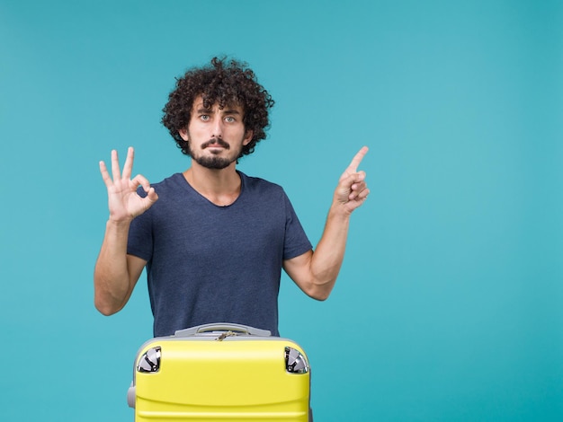 homem de férias com mala amarela em azul