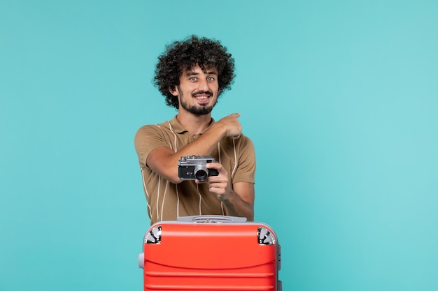 Foto grátis homem de férias com uma grande mala vermelha tirando fotos com a câmera em azul