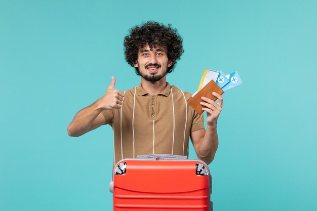 homem de férias segurando bilhetes sorrindo em azul