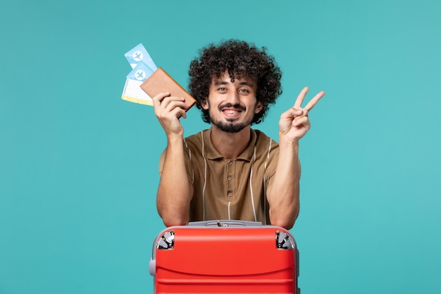 homem de férias segurando bilhetes sorrindo em azul