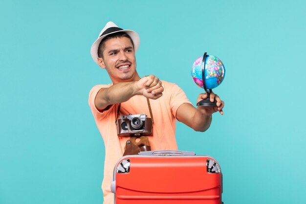 homem de férias segurando o globo com a câmera no azul