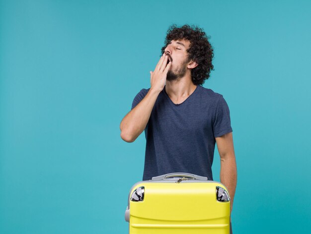 Homem de frente para as férias bocejando no azul