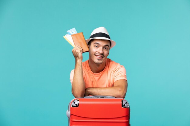 Homem de frente para as férias segurando os ingressos em azul claro