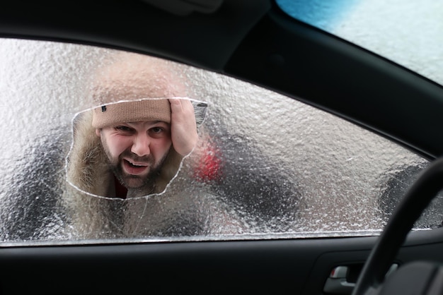 Homem de inverno vandalismo quebrou o vidro do carro uma pedrinha