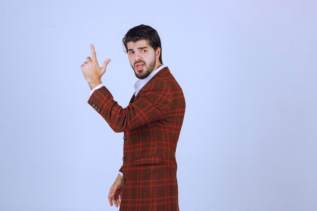 Foto grátis homem de jaqueta marrom, levantando a mão para chamar a atenção.