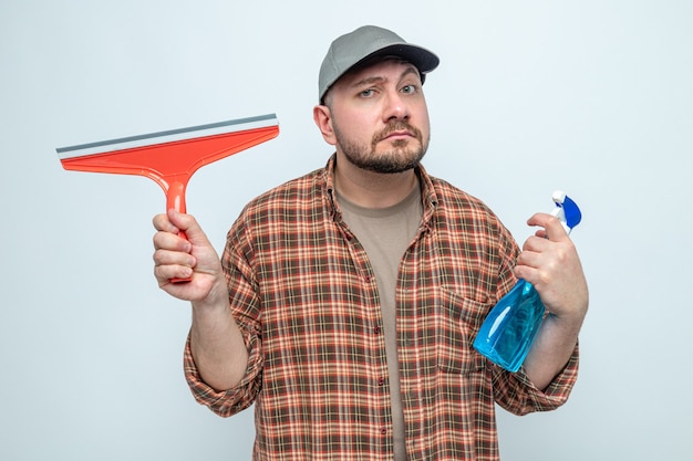 Homem de limpeza eslavo confuso segurando um rodo e um limpador em spray