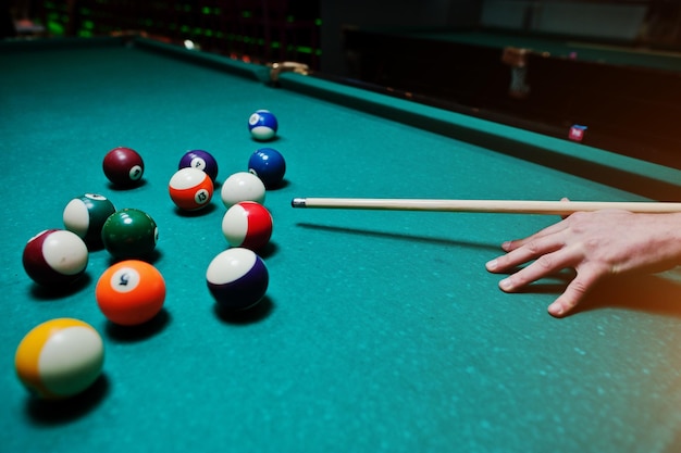Mão do homem jogando sinuca no bar com bola de snooker