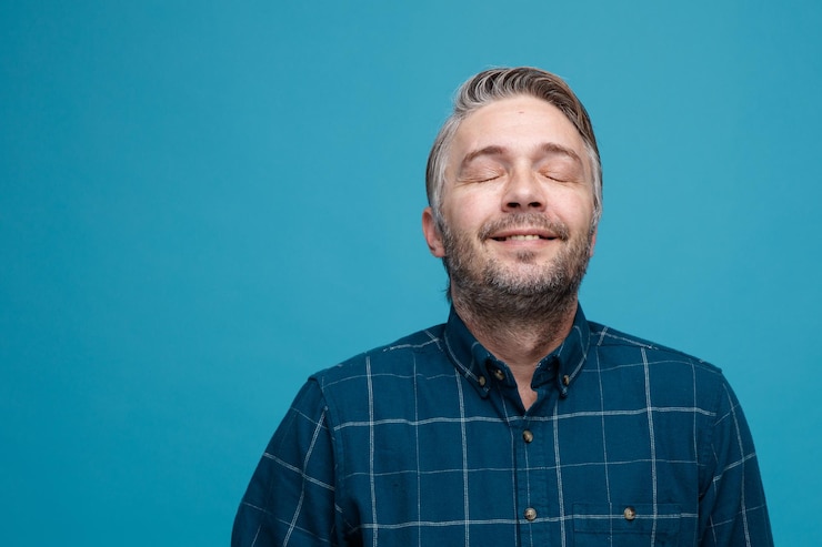 Foto grátis homem de meia idade com cabelos grisalhos na camisa de cor escura feliz e satisfeito com os olhos fechados sobre fundo azul