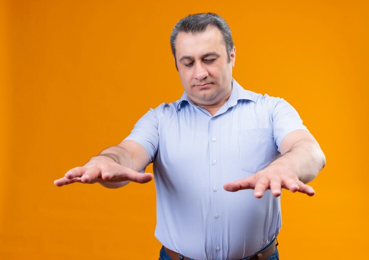 Foto grátis homem de meia-idade com camisa listrada azul e olhos fechados tentando encontrar algo em um fundo laranja