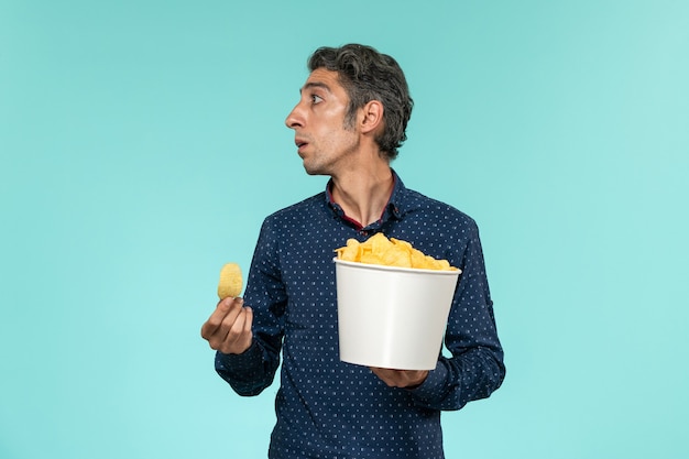 Foto grátis homem de meia-idade com uma cesta cheia de cips na mesa azul