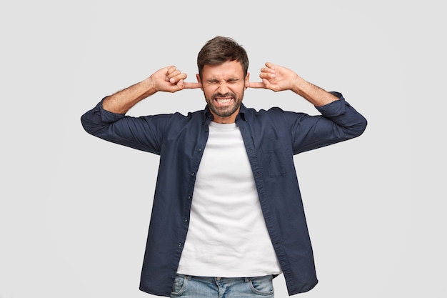 Foto grátis homem de meia-idade perturbado tapando os ouvidos com uma expressão descontente, cerrando os dentes