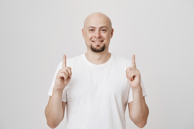 Homem de meia-idade satisfeito, sorrindo, apontando o dedo para cima